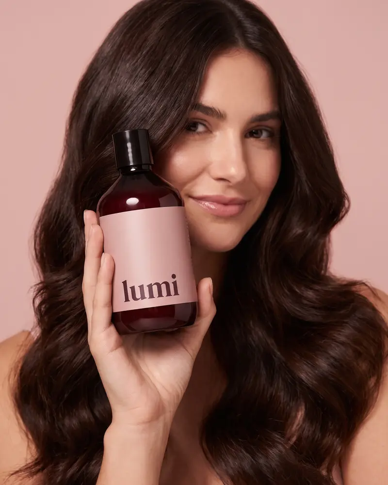 Woman holding a lumi shampoo bottle