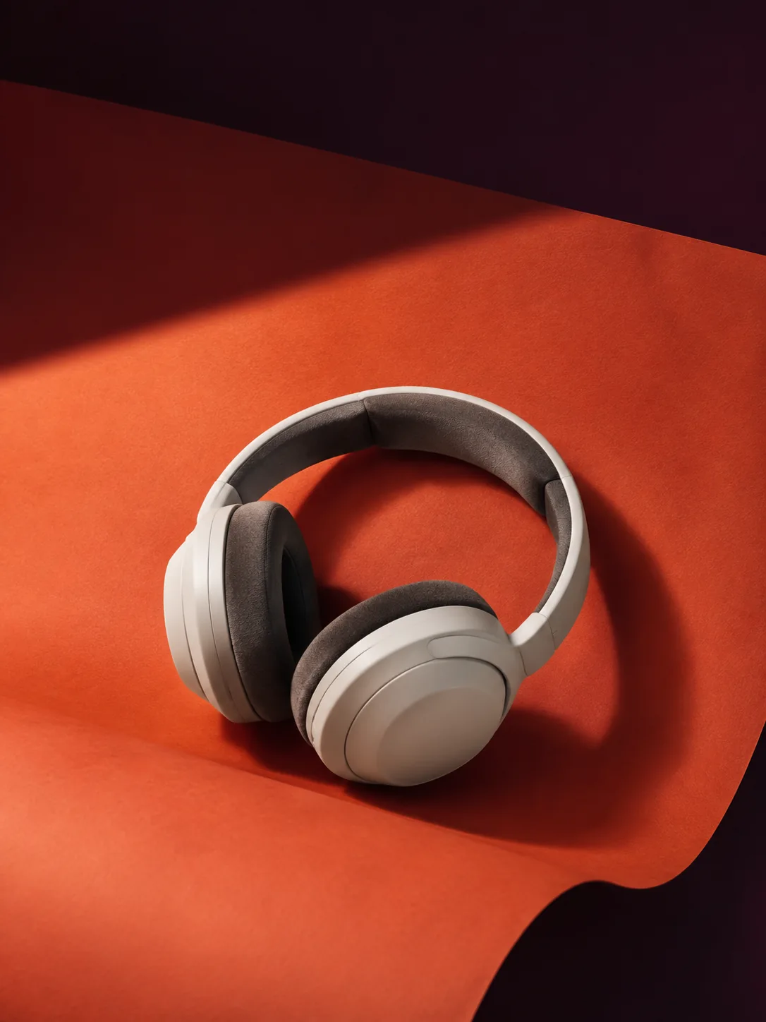 An illustrative audio campaign: off-white headphones on an orange studio backdrop